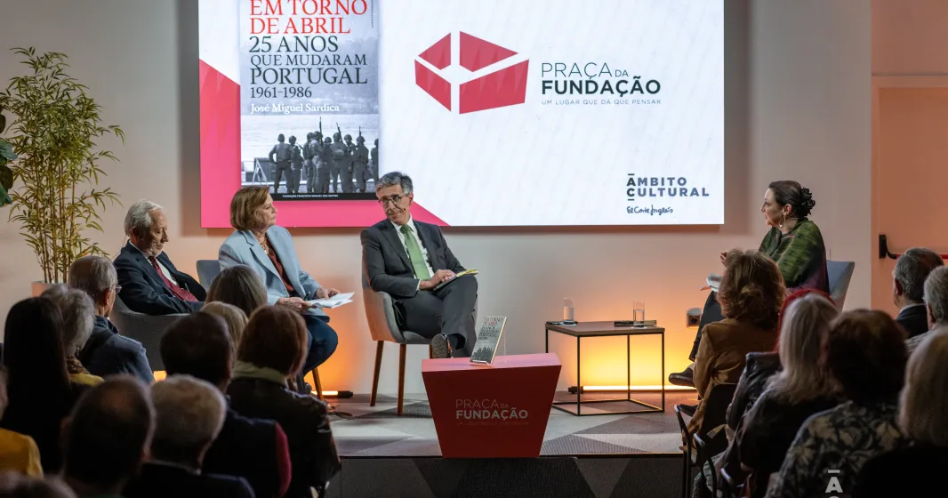 Quatro pessoas sentadas num palco. Atrás, um ecrã com a capa de um livro da Fundação e com o texto "Praça da Fundação".