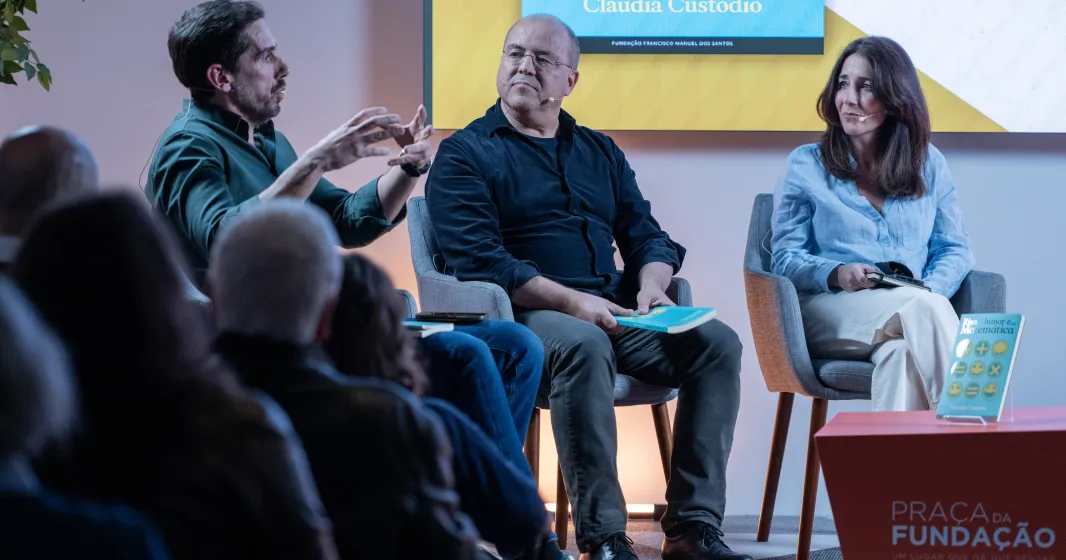 Uma plateia a assistir a um debate entre os humoristas Cláudio Almeida, Nuno Artur Silva e a economista Cláudia Custódio.