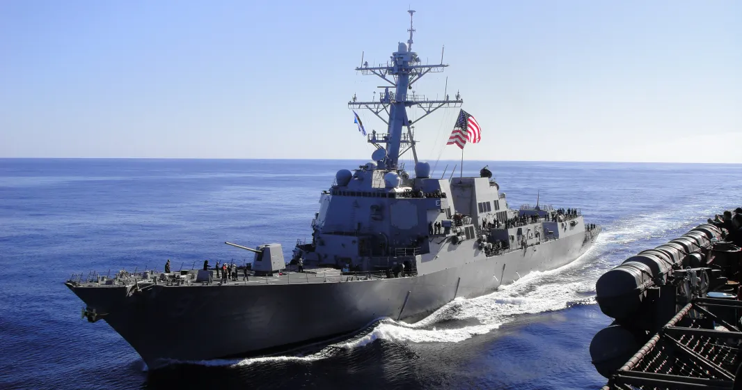 Imagem de um barco da marinha americana, com uma bandeira dos EUA hasteada.