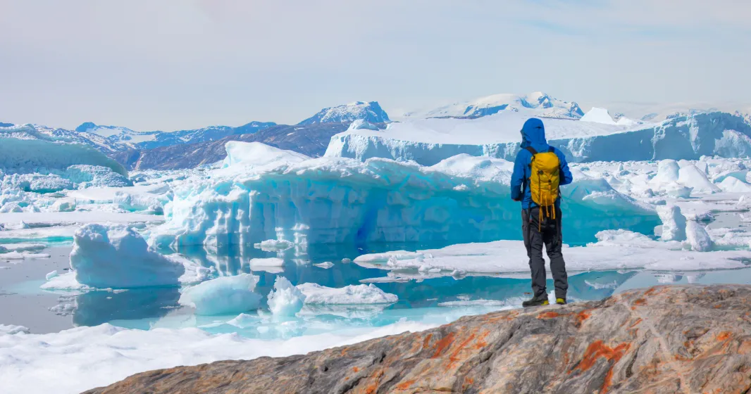 Um homem, explorador, olha para um icebergue no Ártico. Crédito: Shutterstock