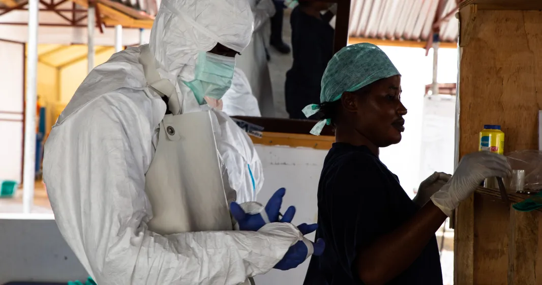 Imagem de uma enfermeira e de um médico vestidos com equipamentos de segurança durante um surto de Ébola em África. Belen B. Massieu/shutterstock