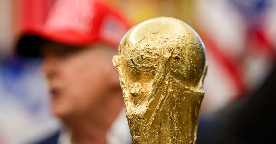 Imagem do troféu do Mundial 2026 em foco e, ao fundo, desfocado, Donald Trump. Créditos: shutterstock