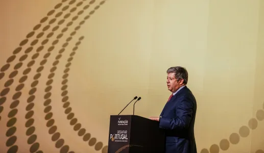 José Soares dos Santos, de fato cinza, a falar ao microfone num púlpito, que tem escrito "DESAFIAR PORTUGAL".