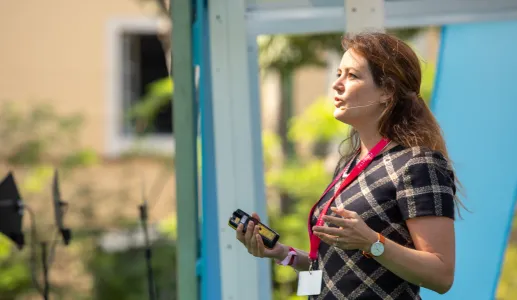 A economista Martha Bailey a discursar, de pé, com um jardim de fundo.