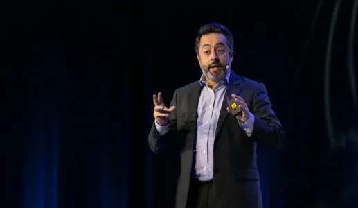 O professor de Ciência Política Tiago Fernandes a falar em palco. Fundo escuro.