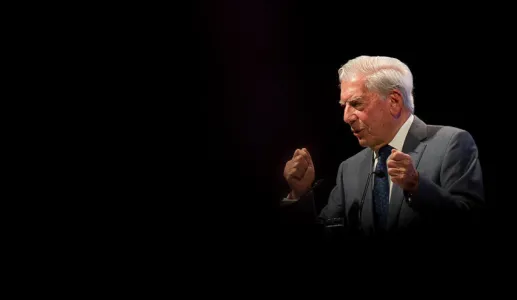Mario Vargas Llosa a discursar. Fundo escuro.