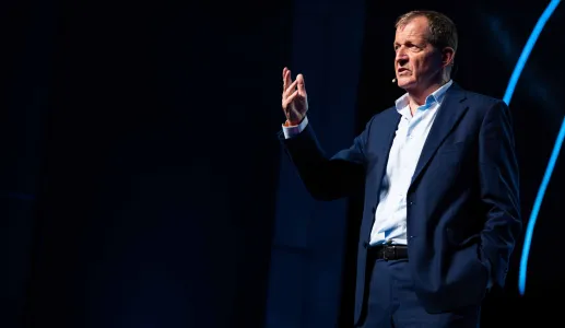 Alastair Campbell em palco, gesticulando enquanto fala ao microfone.