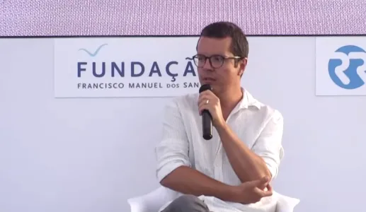 O ilustrador Pedro Vieira, sentado, a falar para um microfone que tem na mão. Ao fundo, um painel com o texto "Fundação Francisco Manuel dos Santos".