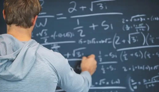 Um homem escreve fórmulas matemáticas num quadro negro.