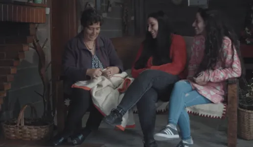 Uma mãe a conversar com as filhas adolescentes enquanto costura.
