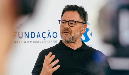 Homem com óculos e barba, a falar durante um evento, com o logo da Fundação Francisco Manuel dos Santos.