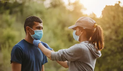 Imagem de um casal a caminhar numa floresta com uma máscara de proteção