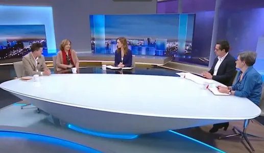 Quatro pessoas sentadas à volta de uma mesa oval Num estúdio de televisão.