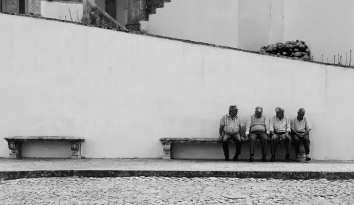 Imagem de idosos sentados, junto a um banco vazio