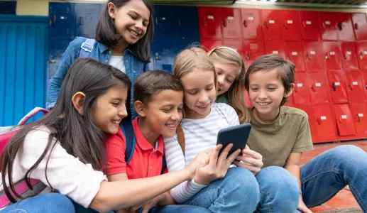 Um grupo de crianças na escola a utilizar smartphones e as redes sociais