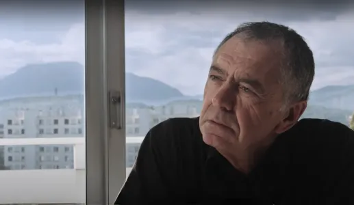 O filósofo e sociólogo Gilles Lipovetsky com ar pensativo, junto a uma janela com montanhas ao fundo.