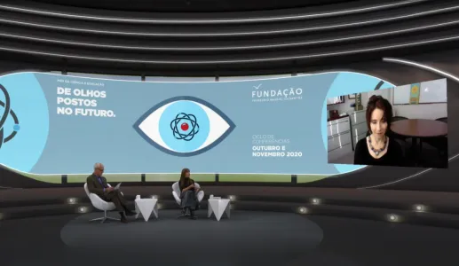 Um homem e uma mulher sentados, num estúdio de televisão, a olhar para uma tela, na qual está Elissa Epel a falar. Do lado oposto da tela lê-se "De olhos postos no futuro". 