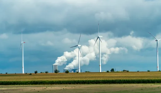  Turbinas eólicas e tubos industriais com fumo a sair num dia nublado na Alemanha. Créditos shutterstock