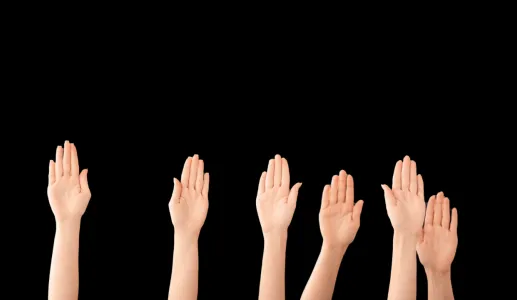 várias mãos no ar, sob um fundo preto, mostrando participação eleitoral. Crédito: Canva