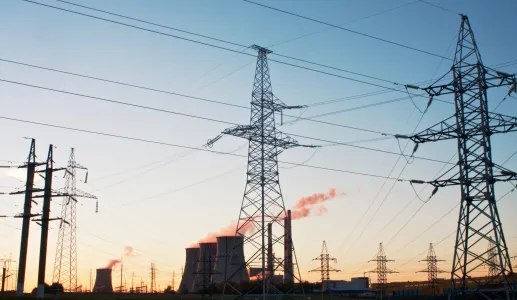 Uma paisagem com torres de refrigeração e uma central elétrica, tendo como fundo um céu azul. Crédito: Shutterstock