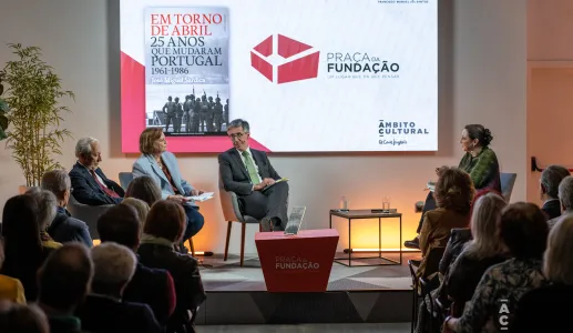 Quatro pessoas sentadas num palco. Atrás, um ecrã com a capa de um livro da Fundação e com o texto "Praça da Fundação".