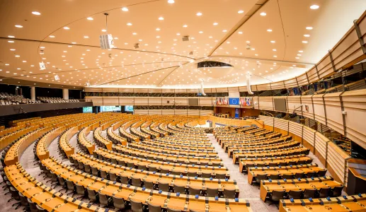 Imagem do interior do Parlamento Europeu. Ao fundo, as bandeiras de cada um dos Estados-membros.