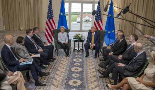 Ursula von der Leyen sentada ao lado de Donald Trump, com bandeiras da UE e dos EUA.