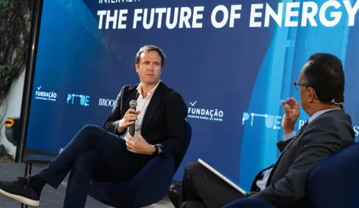 O jornalista britânico Ed Conway em palco, sentado, com um microfone na mão. O entrevistador de costas. Fundo azul com o texto "The Future of Energy". DR/FFMS
