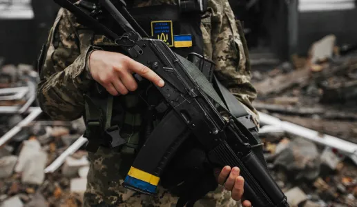Um soldado carrega uma arma ao peito, com a bandeira ucraniana destacada no seu colete de proteção. Créditos: shutterstock