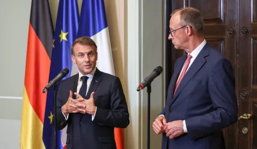 Emmanuel Macron e Friedrich Merz, lado a lado, durante uma conferência de imprensa conjunta. Bandeira de França, Alemanha e da UE ao Fundo. Créditos: shutterstock