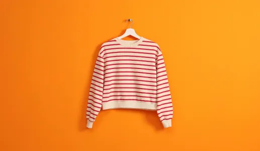 Imagem de uma camisola branca com riscas pendurada num cabide, sob fundo cor de laranja. Crédito: Shutterstock.