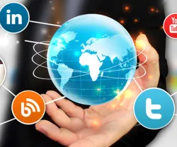 Mão a segurar um globo com ícones de redes sociais como Facebook, Twitter e LinkedIn.