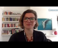 A economista Mariana Mazzucato sobre um fundo com estantes de livros e um quadro de uma baleia.