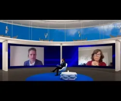 Um homem sentado num estúdio de televisão. Outro homem e uma mulher projetados nas telas. Logotipo "Fundação Francisco Manuel dos Santos" visível.
