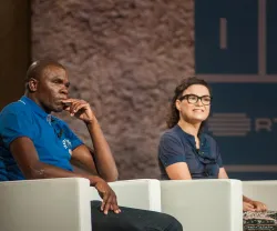 Dois participantes sentados num palco, um homem e uma mulher, com logo da RTP ao fundo.