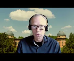 O perito em Sustentabilidade Johan Rockström de fones, numa videoconferência, com um fundo de um observatório e céu azul com nuvens.