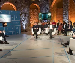 Debate em palco com convidados e audiência, fundo com texto "FRONTEIRAS XXI".