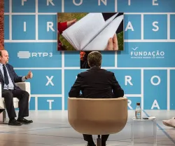 Painel de discussão com três oradores, projetor ao fundo e texto "Fronteiras XXI" e "Fundação".