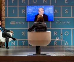 Debate em estúdio com painel de quatro pessoas e um ecrã ao fundo. Texto: "Fronteiras XXI"