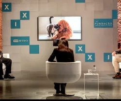 Imagem de um painel com quatro pessoas. Televisão ao fundo mostra um cão e um gato. Logotipo da Fundação e RTP3.
