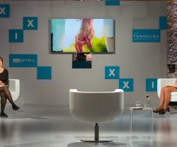 Imagem de um estúdio de televisão com quatro pessoas sentadas e um ecrã ao fundo. Texto visível: "FUNDAÇÃO".