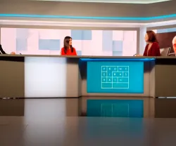 Um debate num estúdio de televisão com três oradores. Texto "FRONTEIRAS XXI" visível na mesa.