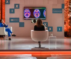 Mesa redonda com várias pessoas e um ecrã, ao fundo, com imagens de cérebros. "FUNDAÇÃO" visível.