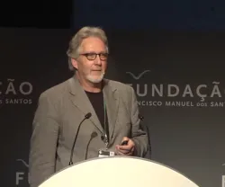 O psicólogo Martin Bauer, de pé, a falar ao microfone. Ao fundo, o logotipo da Fundação.