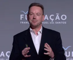 Homem em um palco, a falar para uma audiência. Logotipo da Fundação no fundo.