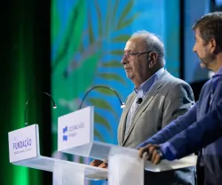 Dois homens num palco, um deles, Jaime Gama, atrás de um púlpito com o texto "FUNDAÇÃO" visível. Fundo verde.