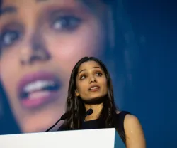 Freida Pinto num púlpito a discursar, com uma imagem da própria atriz no fundo.