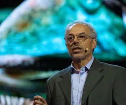 O ecologista e escritor Carl Safina a discursar sobre um fundo colorido de um ambiente marinho.