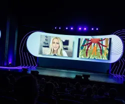 Plateia a assistir à apresentação de Jane McGonigal, projetada numa tela.
