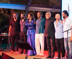 Seis pessoas em palco, entre elas, Paulo de Carvalho e Tiago Bettencourt, após uma apresentação musical.